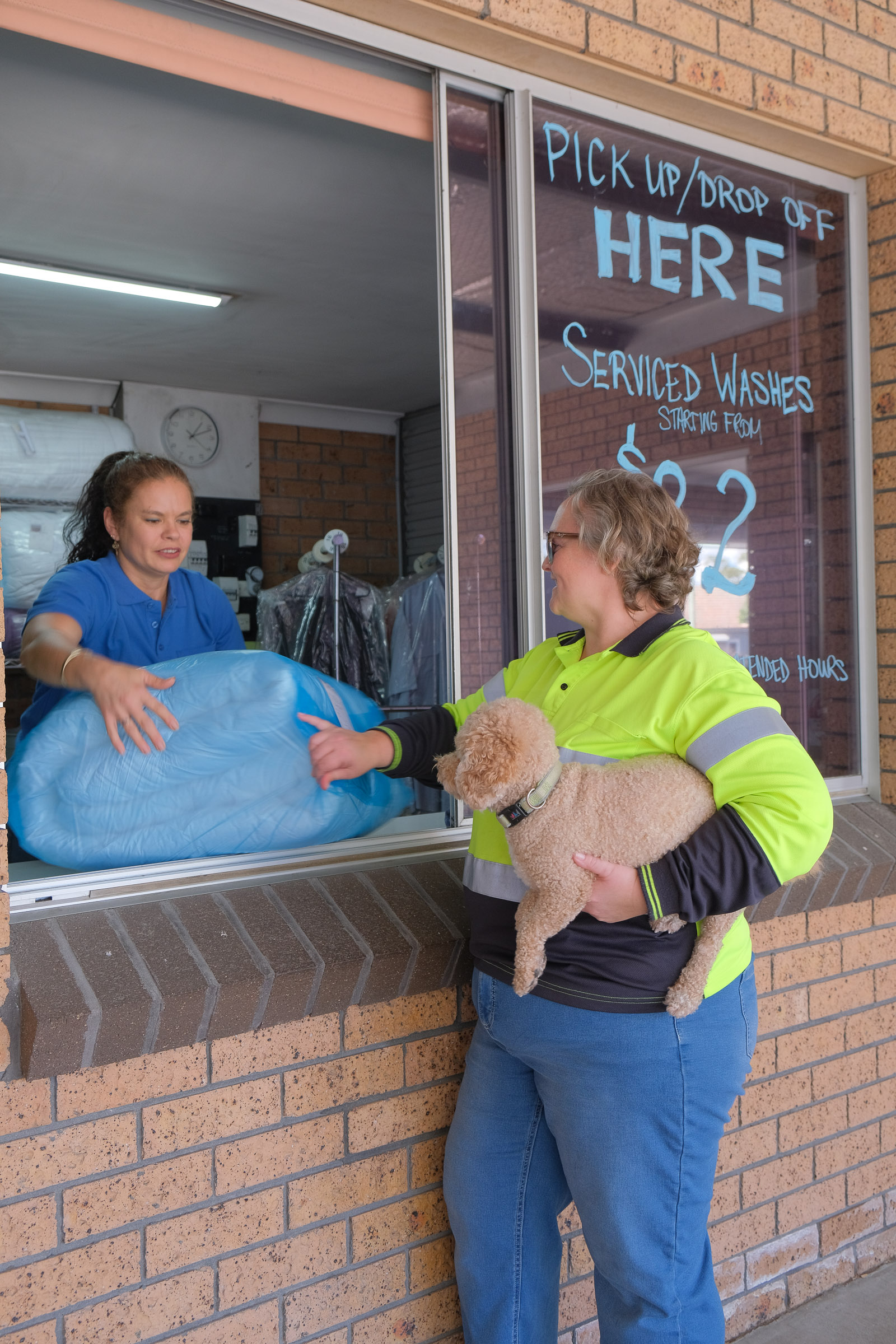 Customer picking up clean doona from laundry pickup window and attendant